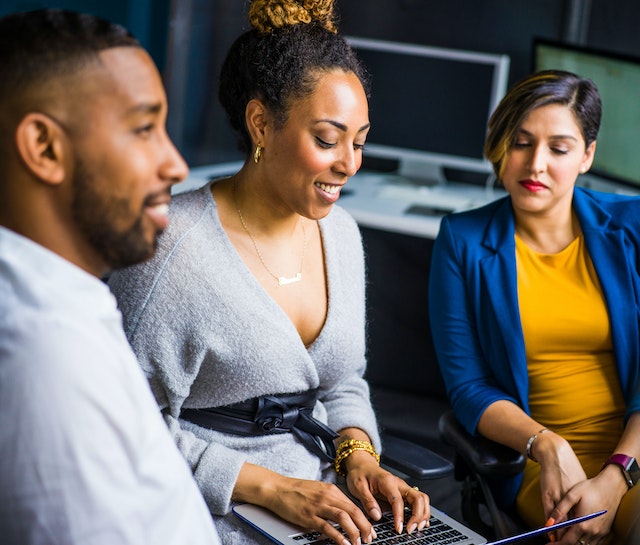 Entrepreneurs gathered and discussing while looking at a laptop screen