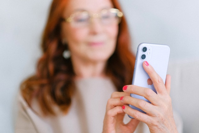 A woman holding a smartphone in her hand and looking at the screen